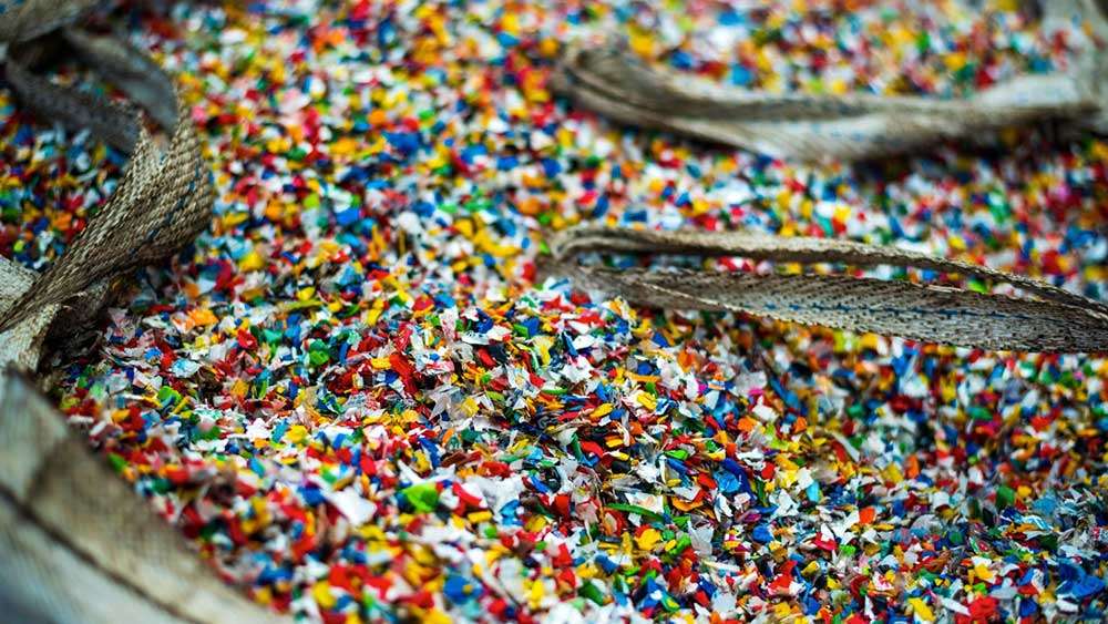 Microplasticos multicolor dentro de en un saco de basura plástica triturada para clasificação para instalações de reciclagem de resíduos.